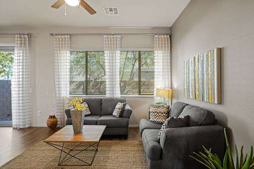 A living room with a grey couch, a coffee table, and a painting on the wall.