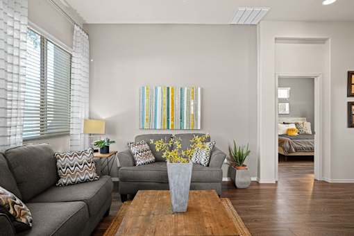 A living room with a grey couch, a wooden coffee table, and a painting on the wall.