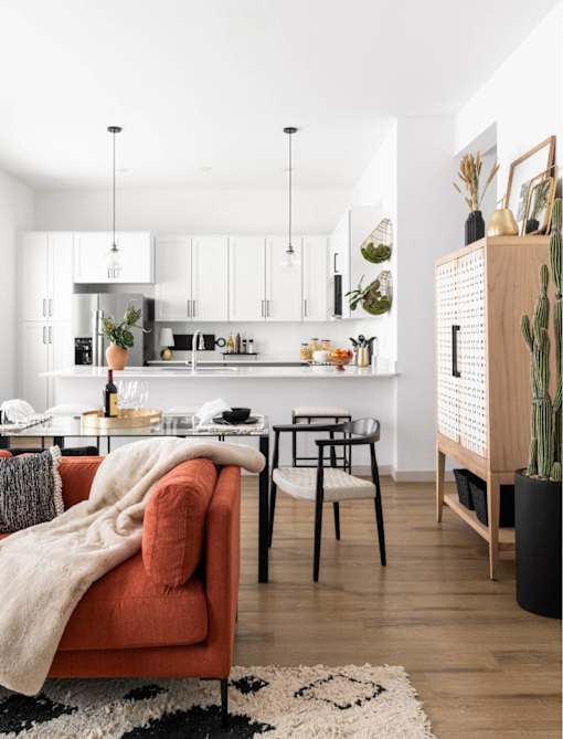 A modern kitchen with a red couch and a black and white rug.
