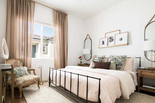 A bedroom with a large bed, a chair, and a window with curtains.