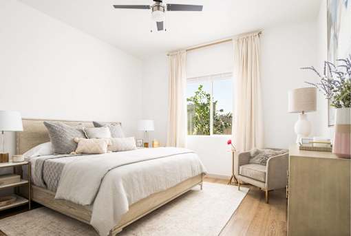 A bedroom with a large bed and a chair.