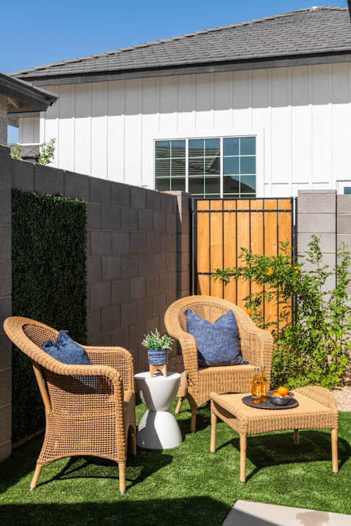 Two wicker chairs with blue cushions are placed on a lawn.