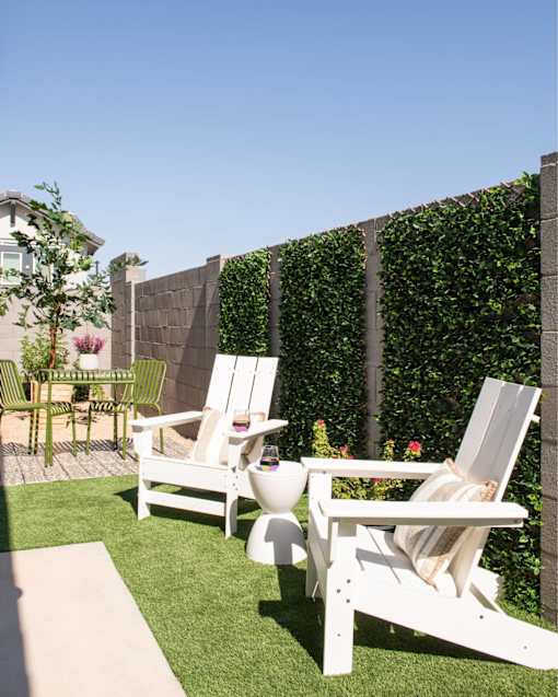 Two white chairs are placed on a lawn.