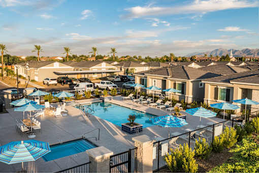 A pool area with blue umbrellas and a mountain in the background.