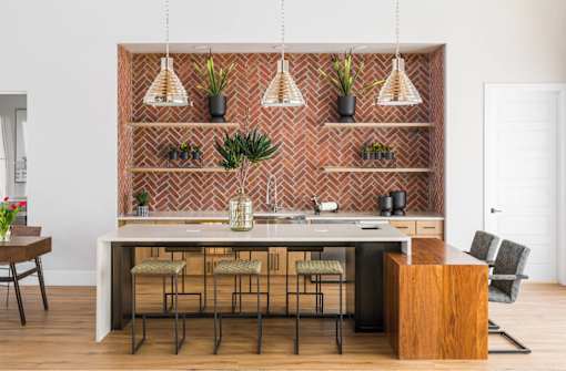 A kitchen with a brick backsplash and a table with four chairs.