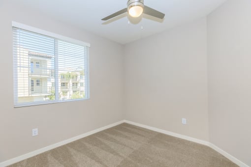 an empty bedroom with a ceiling fan and a window