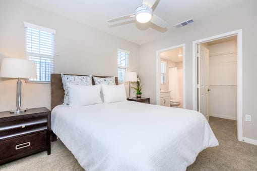 a bedroom with a large white bed and a ceiling fan