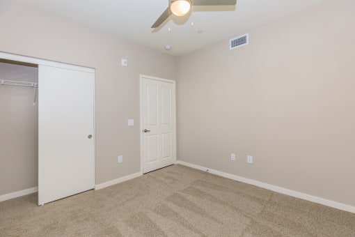 a empty bedroom with a ceiling fan and a closet