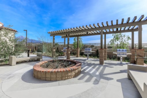 a patio with a fire pit and benches and a pergola