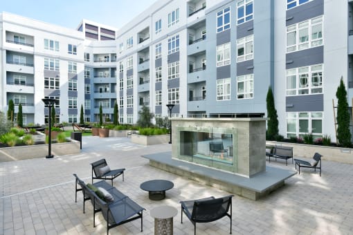 a patio with a fire pit in front of an apartment building