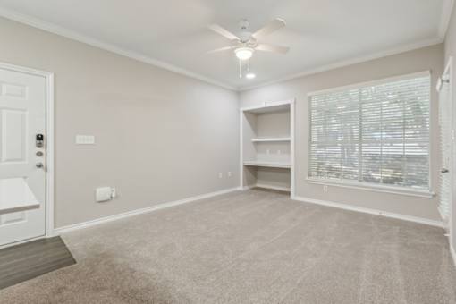 A room with a ceiling fan and a window with blinds.