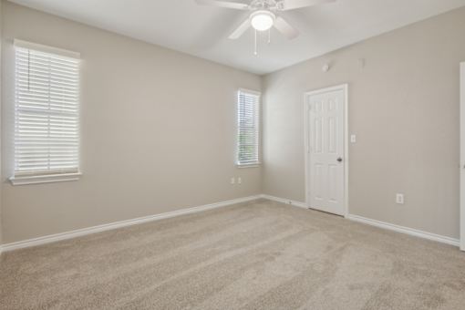 A room with a ceiling fan and carpeted floor.