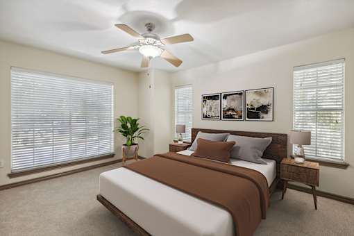 A bedroom with a bed, a ceiling fan, and a potted plant.