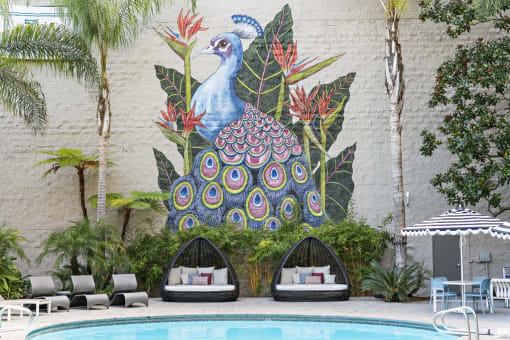 a mural of a peacock on the side of a building with lounge seating by the pool at Vera Cortez Hill, San Diego, 92101