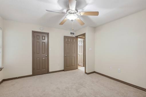 A room with a ceiling fan and two doors.