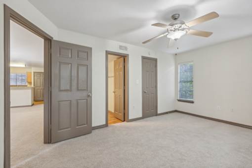 A room with a ceiling fan and three doors.