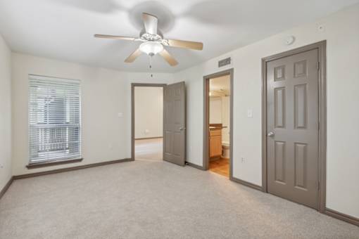 A room with a ceiling fan and three doors.