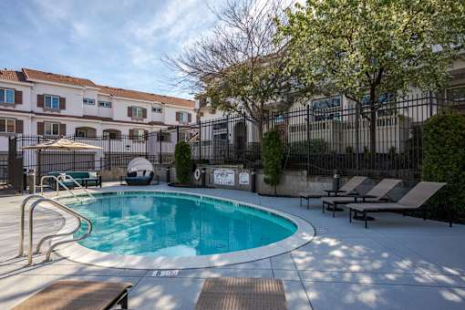 A pool surrounded by a fence and chairs.