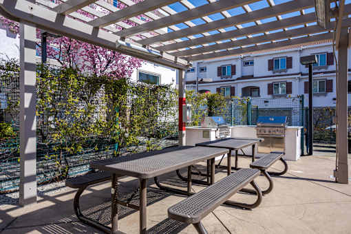 A patio with a table and benches under a pergola.