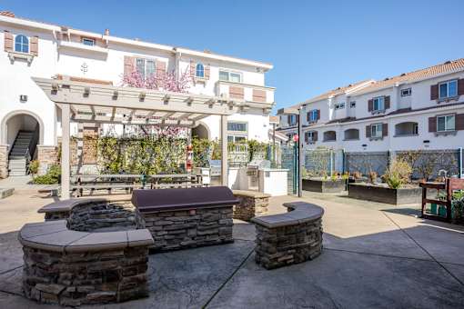 A courtyard with a stone bench and a building in the background.