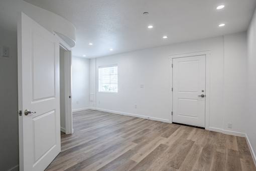 A room with white walls and wooden flooring with two doors.