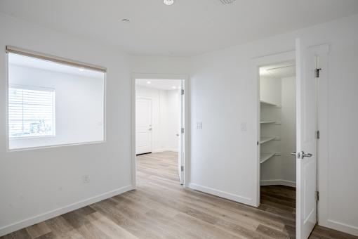 A white room with a window and a door leading to another room.