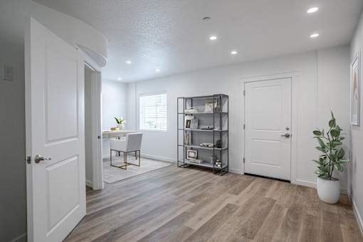 A room with a white door, a table with a plant, and a bookshelf.