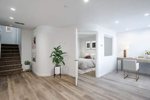 A room with a staircase and a bed in the background.
