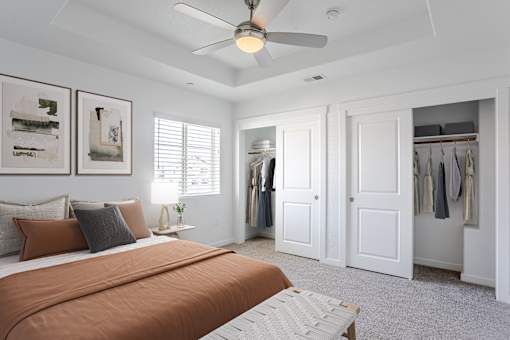 A bedroom with a bed, a ceiling fan, and a closet.