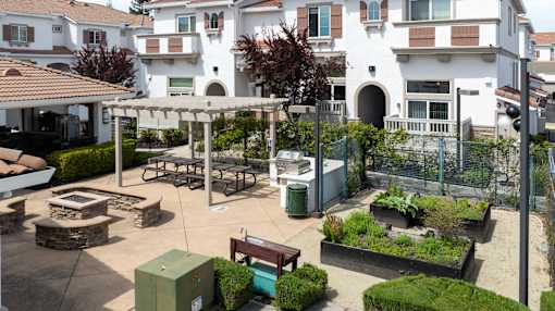 A courtyard with a bench, a table, and a fence.