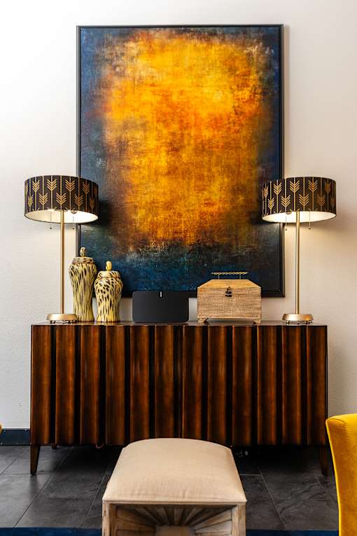 a living room with a desk with two lamps and a painting