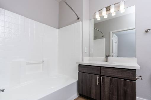 a bathroom with a white tub and a sink and a mirror
