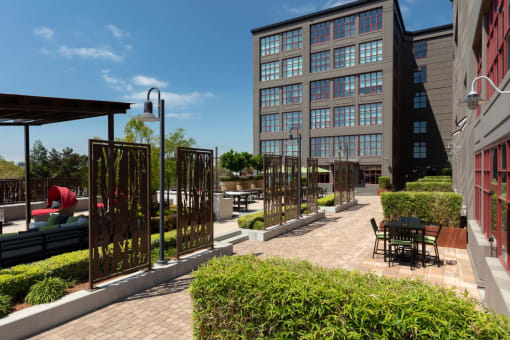a courtyard with tables and chairs and a building in the background at Aqua Via Apartments, Oakland