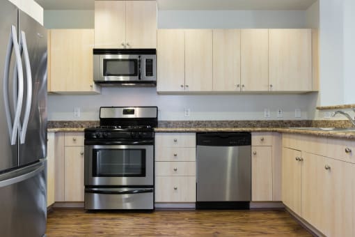 Oakland CA Apartments - Aqua Via - White Kitchen with Granite Countertops, Stainless Steel Appliances & Wood-Style Flooring at Aqua Via Apartments, Oakland, 94607