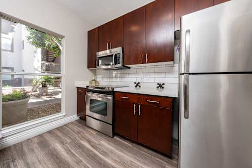 A kitchen with a refrigerator, oven, and microwave.