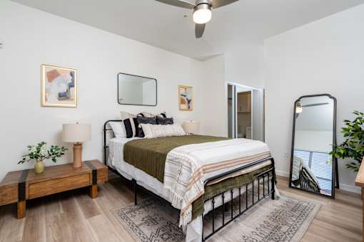 A bedroom with a bed, a nightstand, and a ceiling fan.