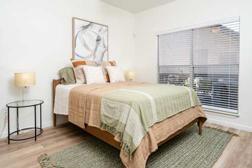 A bedroom with a bed, a lamp, and a painting on the wall.