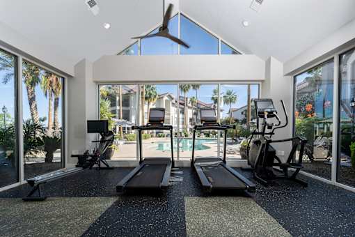 A gym with treadmills, exercise bikes, and a fan.