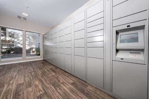 A row of white lockers are lined up in a room with wood flooring.