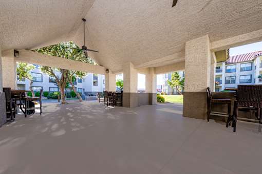 A spacious covered patio area with a ceiling fan and multiple seating options.