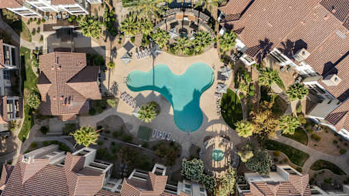 A bird's eye view of a residential area with a large swimming pool in the center.