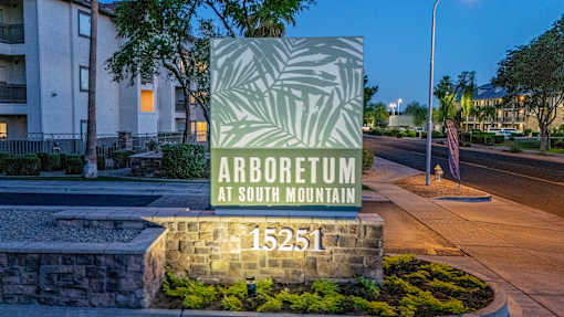 A sign for Arboretum at South Mountain stands in front of a building.