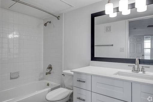A white bathroom with a toilet, sink, and mirror.