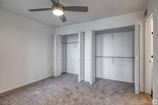 A room with a ceiling fan and carpeted floor.