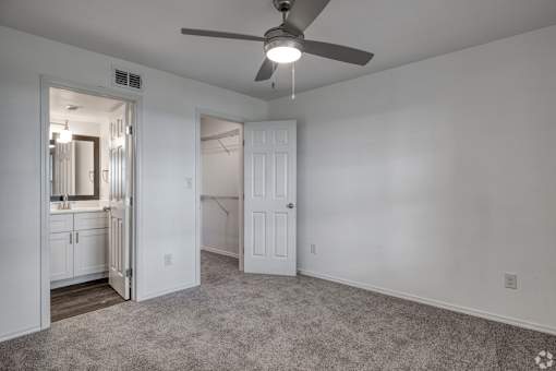 A room with a ceiling fan and carpeted floor.