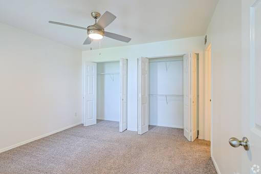 A room with a ceiling fan and carpeted floor.