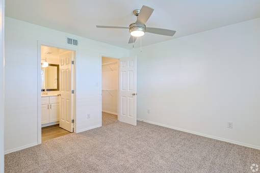 A room with a ceiling fan and carpeted floor.