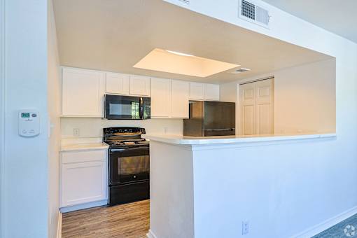 A kitchen with black appliances and white cabinets.