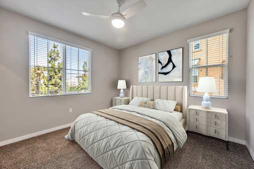A bedroom with a large bed, two lamps, and two pieces of artwork on the wall.