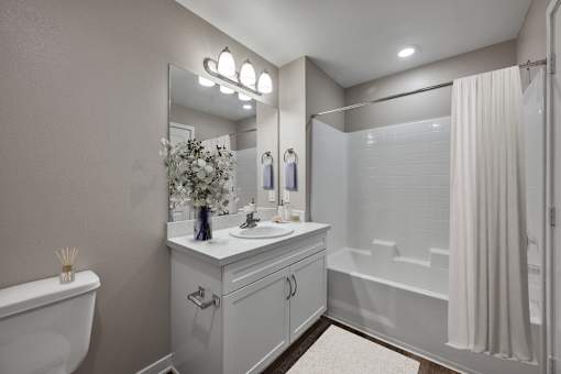 A white bathroom with a tub, sink, and mirror.